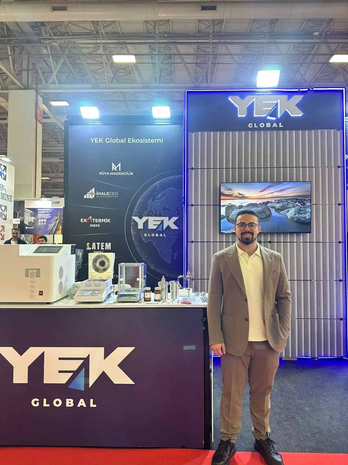 YEKGLOBAL temsilcisi Maden Türkiye 2026 standı önünde — YEK Global ekosistemi